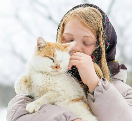 A girl is holding a small kitten gently